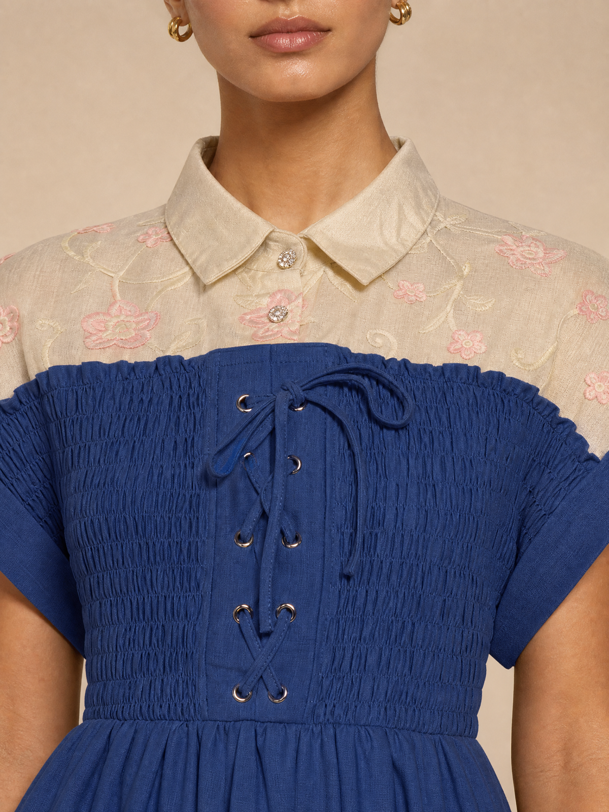 An elegant dress with embroidered floral details and smocking